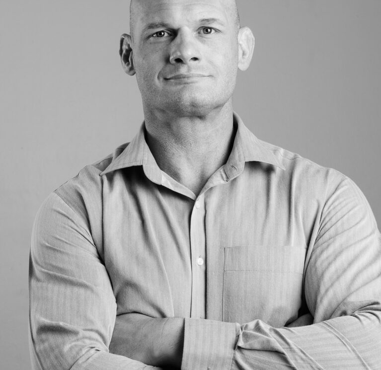 Studio shot of bald businessman against gray background in black and white