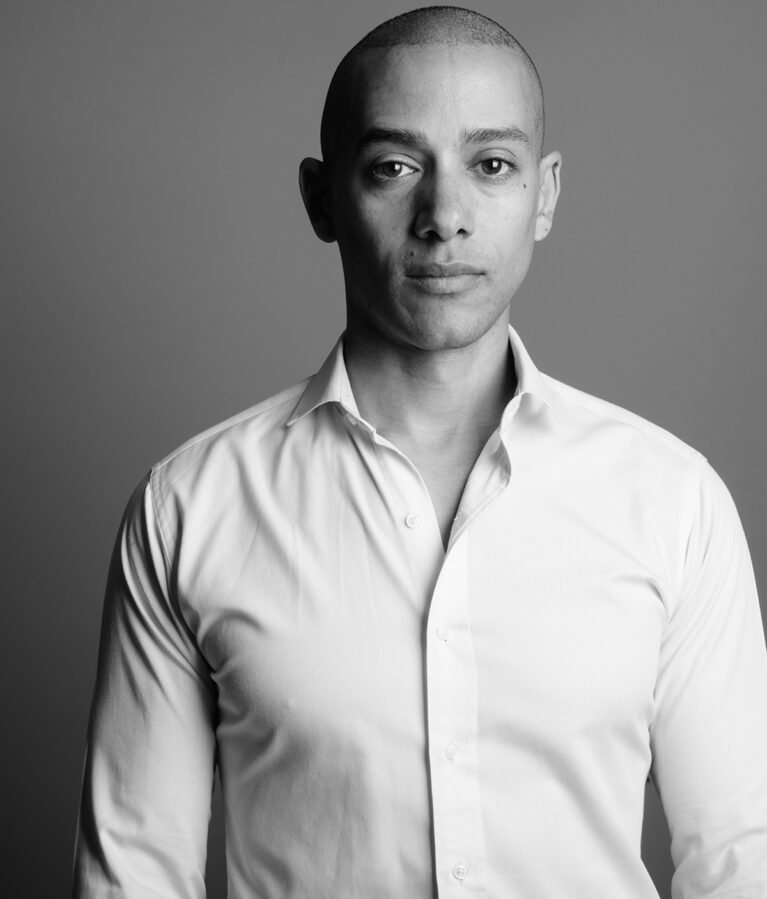 Studio shot of handsome bald businessman wearing white shirt against gray background in black and white