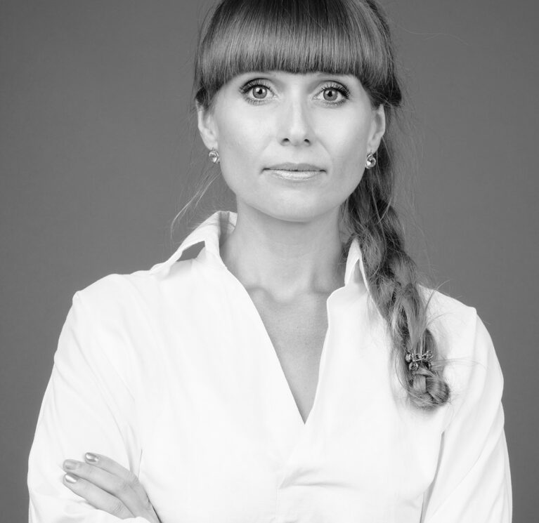 Studio shot of young beautiful businesswoman against gray background in black and white